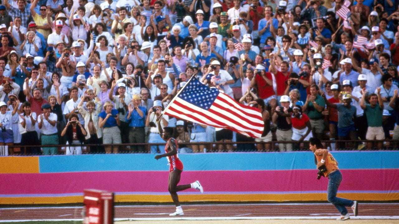 Carl Lewis celebrates with the US flag at the 1984 Olympics.